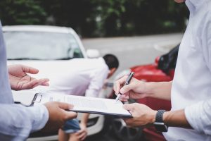 Insurance Agent examine Damaged Car and customer filing signature on Report Claim Form process after accident, Traffic Accident and insurance concept.